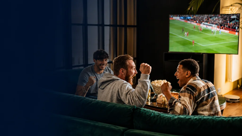 Friends cheering while watching soccer on a living room TV