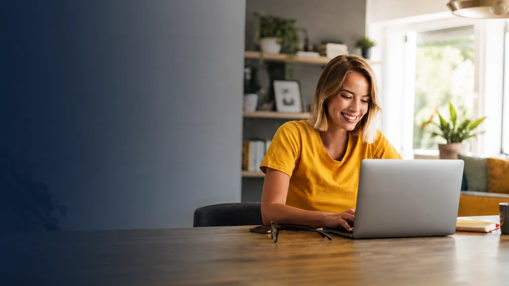 Woman working on a laptop at a dining table