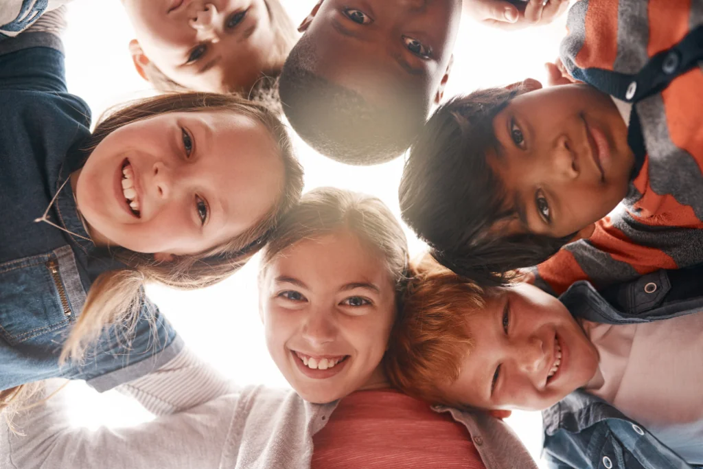 A diverse group of children huddled together in a circle, smiling